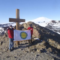 Wayne Clough and Kristina Johnson hoist the Smithsonian flag atop Observation Point, where a cross has been erected in memory of the lost expedition of Robert Scott.