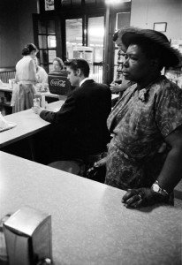 Segregated Lunch Counter. While waiting for a train to take him from Chattanooga to Memphis, a trip of some 400 miles, Elvis sits at the lunch counter to have some breakfast. The woman standing had ordered a sandwich for which she was waiting, but was not able to sit at the counter. Railroad station, Chattanooga, Tenn. July 4, 1956.© Alfred Wertheimer. All rights reserved.