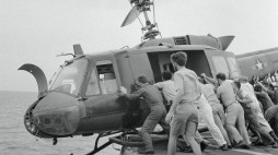 Crew members push a Huey helicopter into the ocean to make room on the Kirk's small deck for more incoming crafts carrying Vietnamese refugees. (Photo by Craig Compiano)
