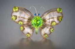 Green sphene butterfly brooch created by Buzz Gray and Bernadine Johnston. Thirteen butterfly brooches set with rare gems such as alexandrite, Mexican fire opal, pearls from Baja California, topaz, rainbow moonstone, sapphire and more are on display.