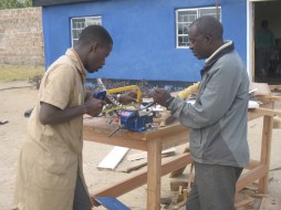 Bernard Kiwia (left) of Global Cycle Solutions in Tanzania and Francis Mwansa from Peace Corps Zambia modify a bicycle into a pedal powered peanut butter grinder. Photo courtesy of Peace Corps Zambia
