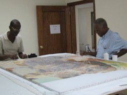 Jean-Menard Derenoncourt and Franck Louissaint treat the Palais National's Mario Benjamin painting. (Photo by Stephanie Hornbeck) 