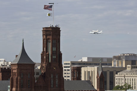 The Space Shuttle Discovery, atop a modified 747, circles the National Mall April 17, 2012. The Smithsonian Institution Building (the "Castle") is seen in the foreground. (Photo by Chun-Hsi Wong)