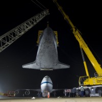 The space shuttle Discovery is suspended from a sling held by two cranes shortly after the NASA 747 Shuttle Carrier Aircraft (SCA) was pushed back from underneath at Washington Dulles International Airport, Thursday, April 19, 2012, in Sterling, Va.