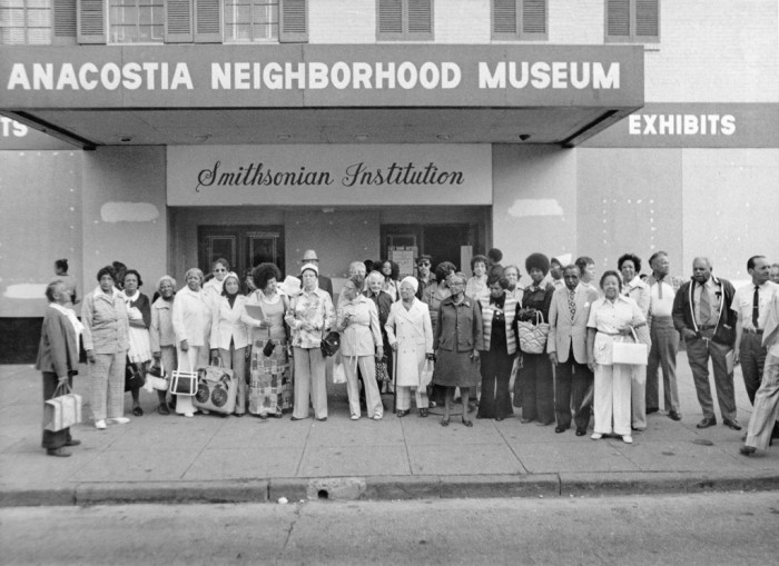 Large group of people posed in front of building with The Neighborhood Museum Sign