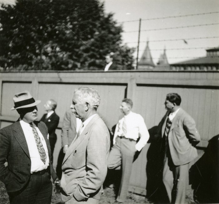 Secretary Charles Greeley Abbot is seen here talking with an unidentified person in the South Yard behind the Smithsonian Institution Building or "Castle." (This image was taken by Ruel P. Tolman, former Director of Smithsonian National Collection of Fine Arts, and is included in a scrapbook of photographs of Smithsonian staff, grounds and buildings, exhibitions, and Washington, D.C. scenes.)