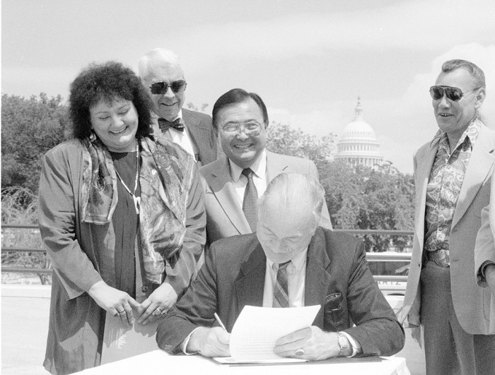 Ninth Smithsonian Secretary (1984-1994) Robert McCormick Adams, signs Memorandum of Understanding with the Museum of American Indian, Heye Foundation, transferring its superb collection of American Indian artifacts to the Smithsonian. Looking on, left to right: Suzan Harjo, member of board of trustees, Museum of the American Indian, Heye Foundation, New York City; Roland Force, director MAI; Senator Daniel K. Inouye (D-HI), chief supporter of legislation to create NMAI; Dick Baker, member Lakota Sioux Red Feather Society; Rep. Ben Nighthorse Campbell (D-CO), the only American Indian member of Congress. (Photo by Laurie Minor-Penland, as featured in the Torch, September 1994)