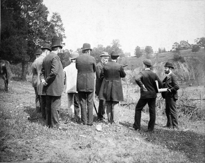 Secretary Samuel P. Langley with others survey the grounds of the newly established National Zoological Park, ca. 1888. In the photograph, left to right, are Mr. Olmsted's assistant; James W. Traylor; C. W. Schuermann; Frederick Law Olmsted; Dr. Frank Baker; Secretary Langley; William Temple Hornaday; Harry W. Dorsey; and W. C. Winlock. The George Brown Goode house appears in the far right of the photograph on the former Columbia Road.