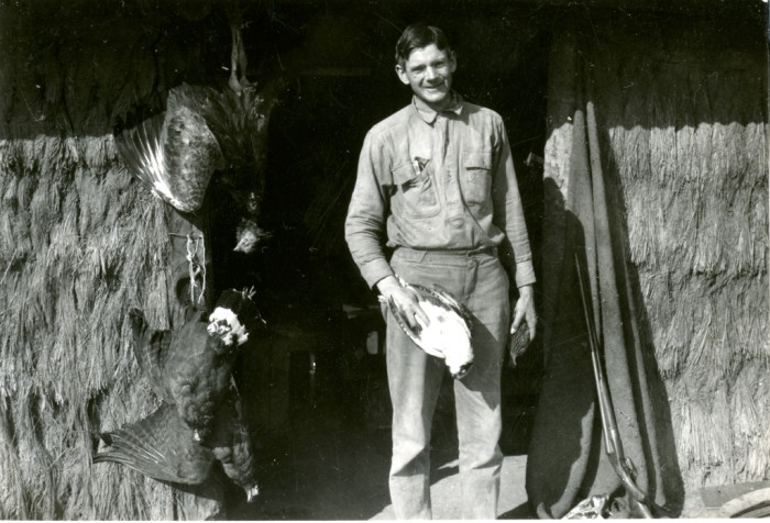 Alexander Wetmore, noted ornithologist and sixth Secretary of the Smithsonian Institution, 1944-1952, is seen here standing in the doorway of his work quarters at Hacienda Linda Vista in Riacho Pilaga, Argentina, on August 16, 1920. He was conducting field work for the U. S. Bureau of Biological Survey. The walls of the quarters are thatched; however, the roof is not visible. Several dead birds are hanging upside down on the side of the doorway. Wetmore is holding a dead bird in each hand. Secretary Wetmore conducted extensive field work throughout the islands of the Caribbean and many Latin American countries