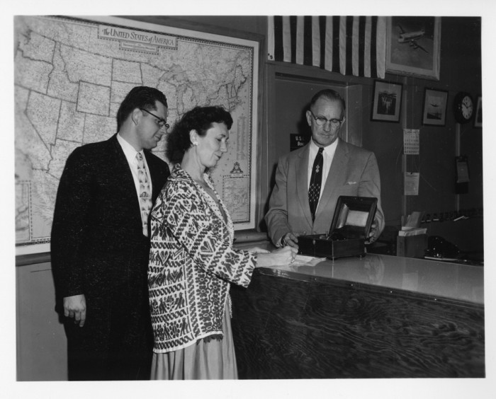 Helena Weiss (Chief, Division of Correspondence and Documents, 1948-1956, Registrar, Office of the Registrar, 1956-1971), signs paperwork during the presentation of the Roentgen X-ray tube to the Smithsonian. George B. Griffenhagen, curator of the Division of Medicine and Public Health, stands to Weiss' left.