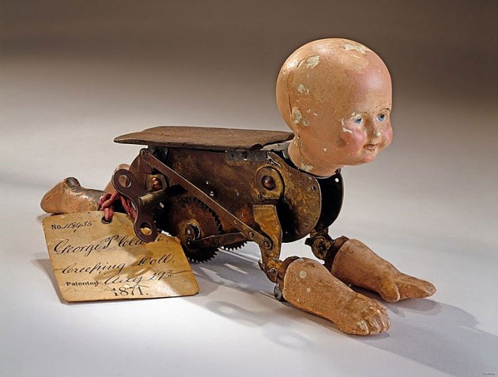 This patent model accompanied George Pemberton Clarke's patent submission for a moving baby doll. The doll's head, two arms, and two legs are made of plaster. The arms and legs are hinged to a brass clockwork body that imitates crawling by rolling along on two toothed wheels.