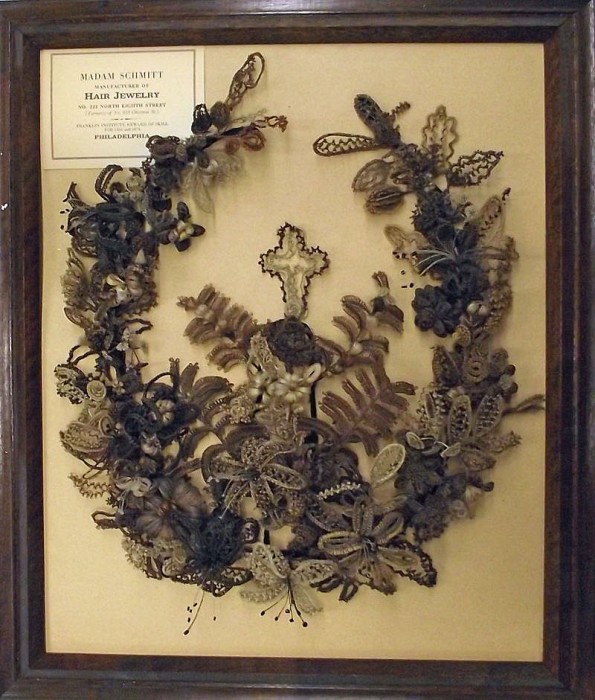 This wreath, made by Mrs. Jemima Cattell Little in Newton, Iowa, around 1865, would have been hung on a wall as decoration. The hair was wrapped, woven, or braided around gauged wire to help keep its shape.