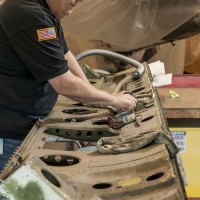 Museum specialist Carl Schuettler does initial cleaning of one of the Helldiver’s two bomb bay doors. (Photo by Dane Penland)