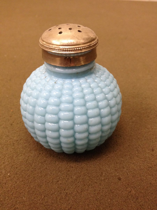 A glass salt shaker in or collection. It has a corn cob design and is from the 20th century.