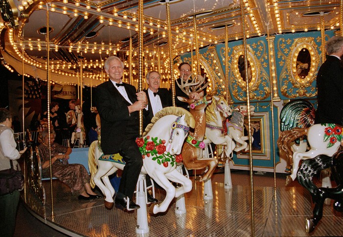 From left, Smithsonian Secretary I. Michael Heyman, Provost Dennis O'Connor and curator Marc Pachter ride a carousel set up at the Los Angles Convention Center, first stop of the "America's Smithsonian" national tour celebrating the Smithsonian's 150th anniversary. The exhibition opened in Los Angeles Feb. 9, 1996. (Photographer unknown, via Smithsonian Institution Archives)