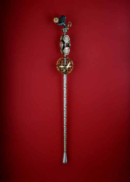 The Smithsonian Mace was commissioned in 1964 by the Institution in anticipation of the celebration of the bicentennial of the birth of the Smithsonian’s benefactor and namesake, James Smithson. The 47-inch mace was unveiled Sept. 17, 1965, a gift from friends of the Smithsonian; it is constructed of gold and silver and encrusted with diamonds, rubies and polished Smithsonite, a mineral identified by James Smithson and named for him posthumously in 1832.