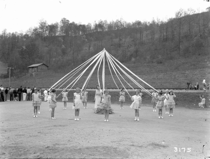 Caucasian girls stand around a maypole