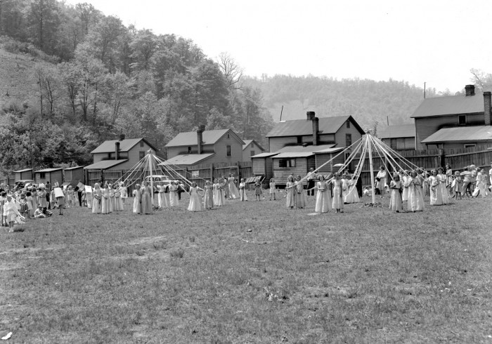 Women dancing around maypoles in a coal town