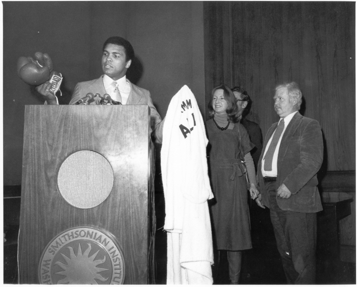 Ali at podium with gloves and robe