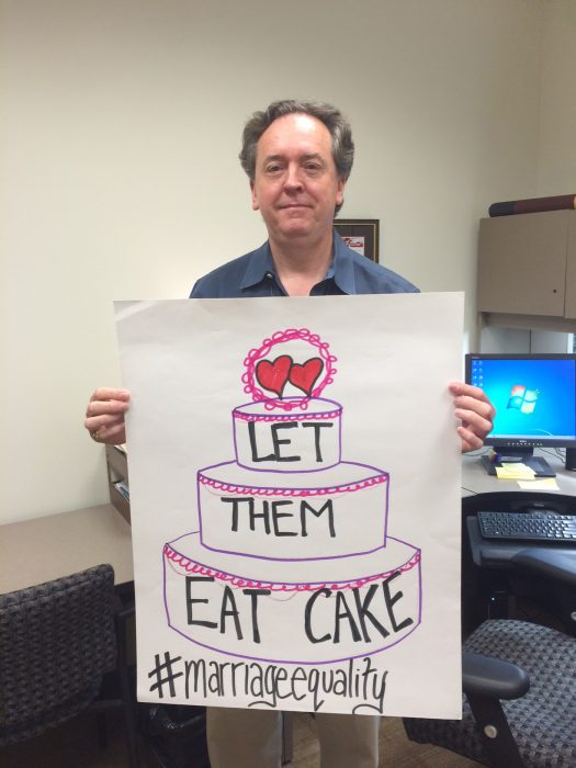 Robinson with hand-drawn poster saying Let Them Eat Cake