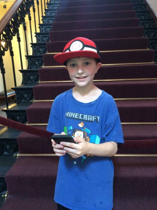 Young boy with PokeBall cap holding phone