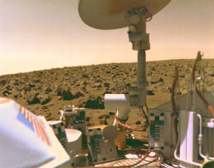 Viking Lander in foreground against rocky surface of Mars and pinkish sky