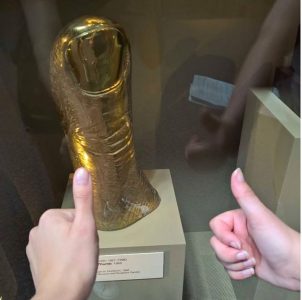 sculpture of thumb with two people giving thumbs-up sign in the foreground