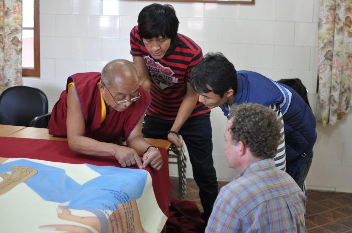 Tibetans lean over table displaying a large banner