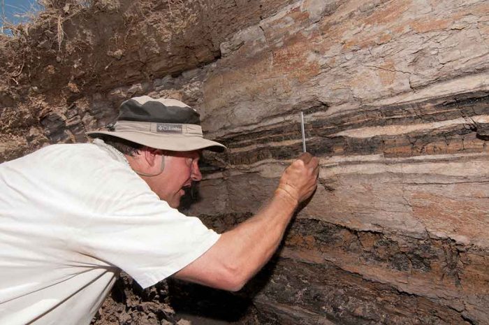 Johnson wearing hat examines rock strata