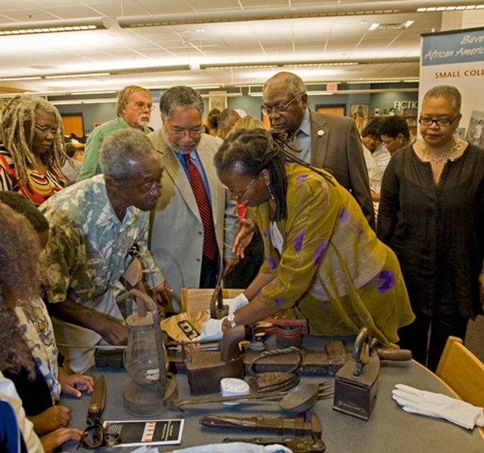 Group of people leaningover table examining artifacts