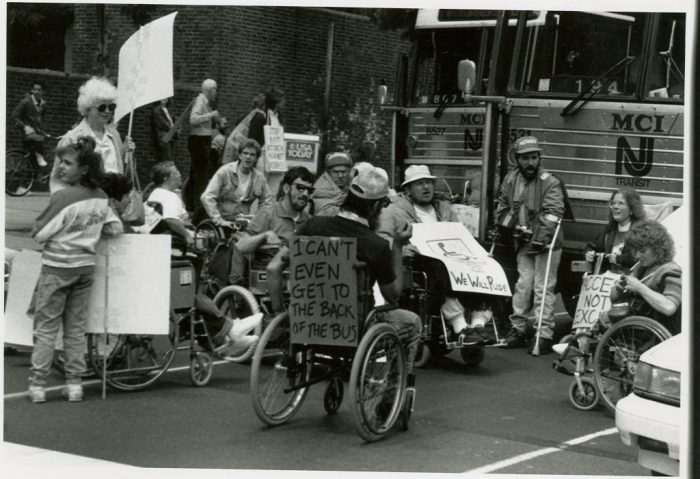 Protesters in wheelchairs carrying signs