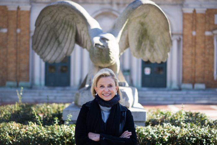 Blonde woman posed in front of statue of eagle