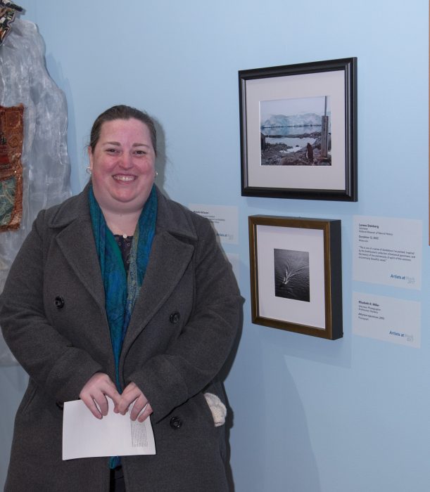 Artist stands next to her work in gallery