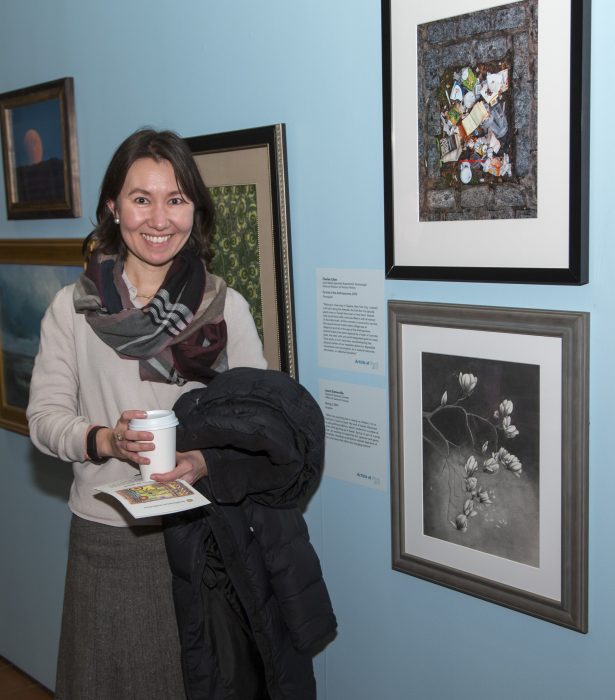 Artists standing with her work in gallery exhibition