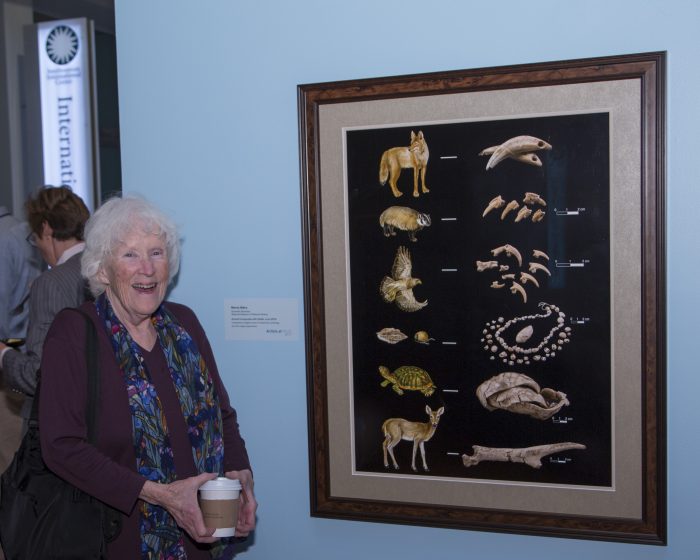 Artists stands next to her work in exhibition gallery