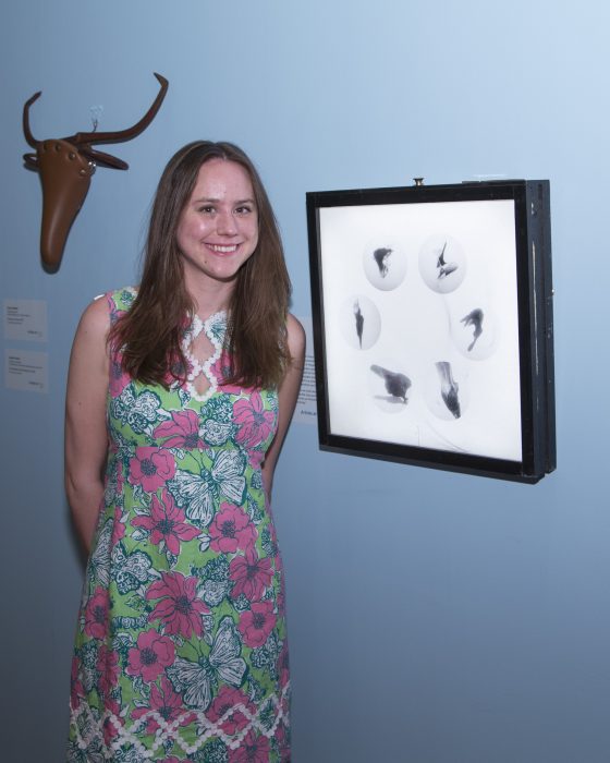 Artist standing with her work in exhbition gallery 