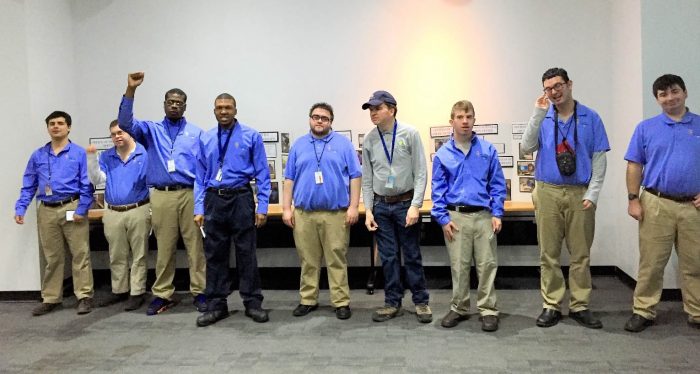 Several young men in khakis and blue shirts pose for picture