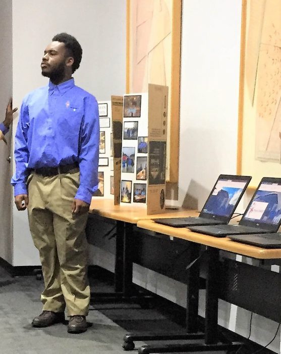 Young man stands next to display table at Project Search event