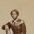 Sepia-toned photo of young Tubman leaning arm on chair