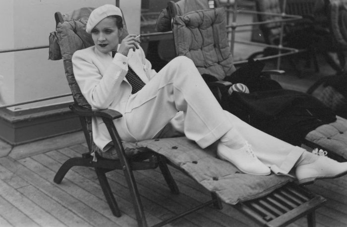 Acrtess in white suit and beret on deck chair