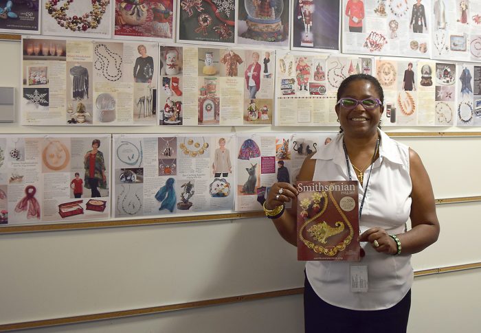 Marie Dieng holds catalog in front of wall display showing pages