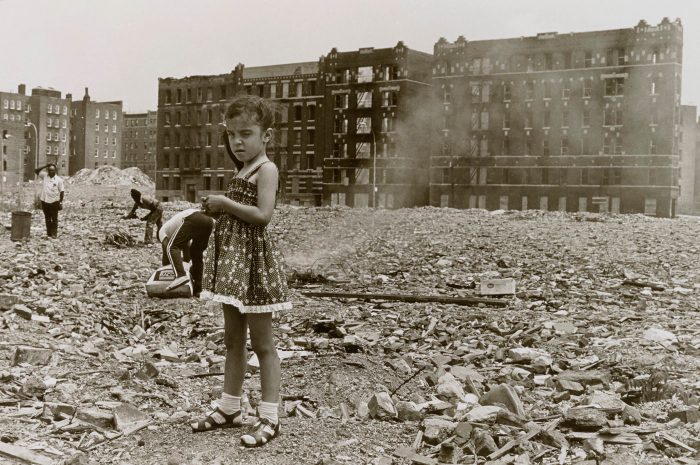 Photo of little girl in rubble-strewn vacant lot