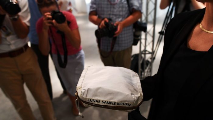 Photographers take pictures of bag marked Lunar Sample Return