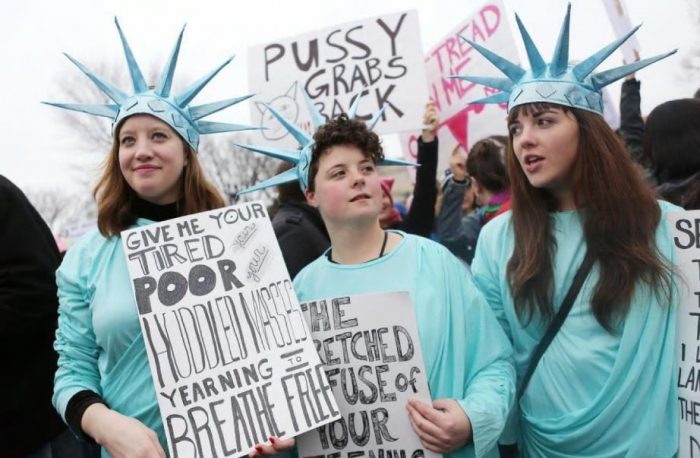 Women holding signs and wearing Liberty costumes