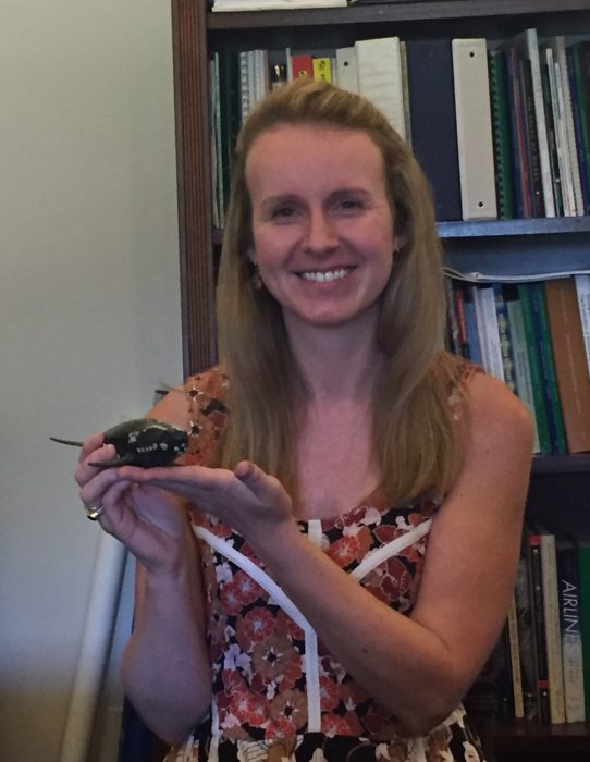 Liza in her office holding small model of a whale