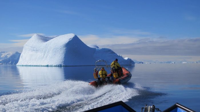 researchers in small boat with ice floe in background