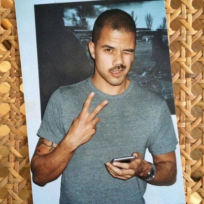 Young man winking and flashing peace sign