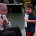 Laughing child holds music as Skorton plays the flute