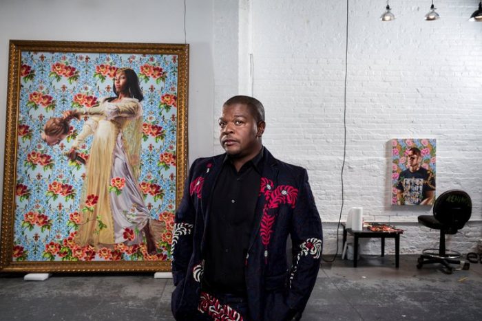 Artists stands in front of one of his portraits