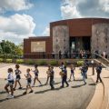 drum line of young kids marches in front of museum